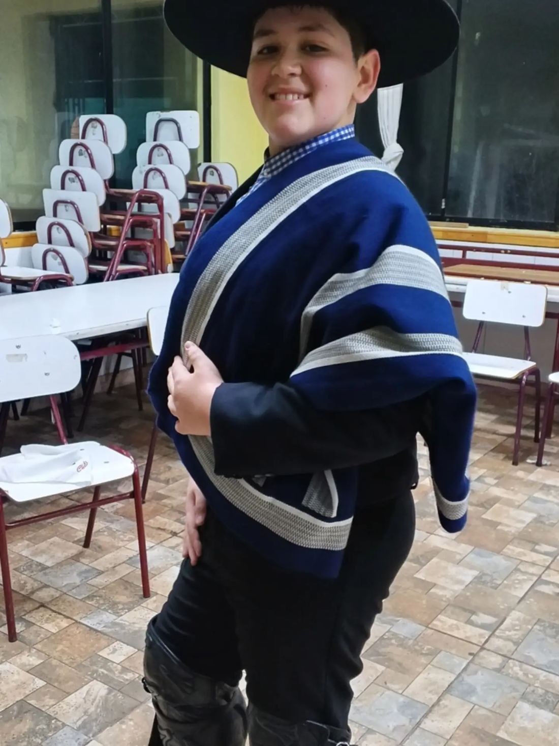 Huasito con manta azul y botas en su sala de clases