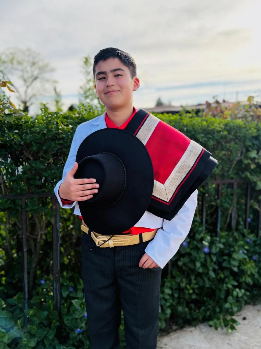 Joven huaso con el sombrero en la mano y manta roja